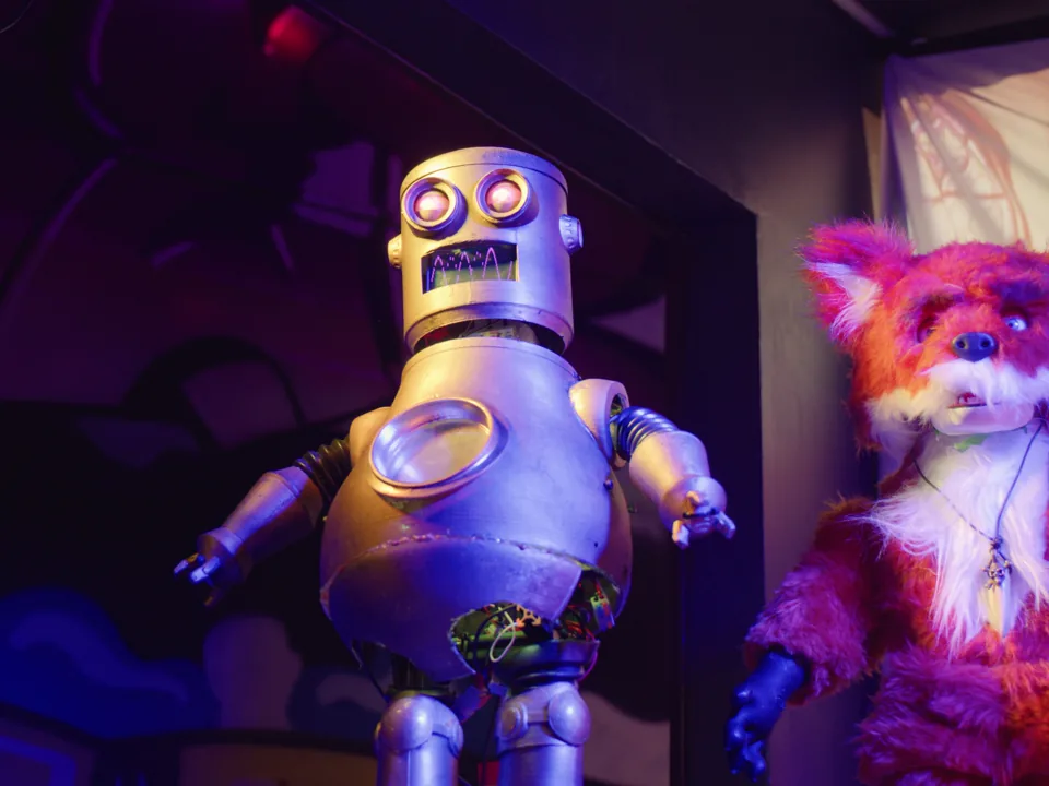 Otto the robot and a fox character performing under theatrical lighting
